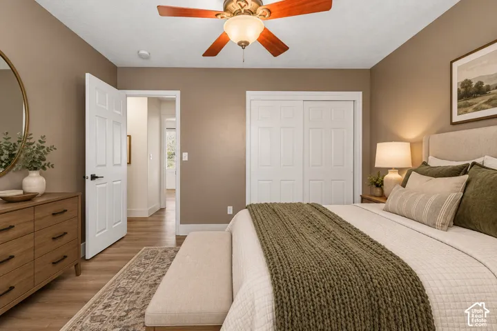 Room featuring wood-finish flooring, a ceiling fan with integrated light fixture, and a double-door closet