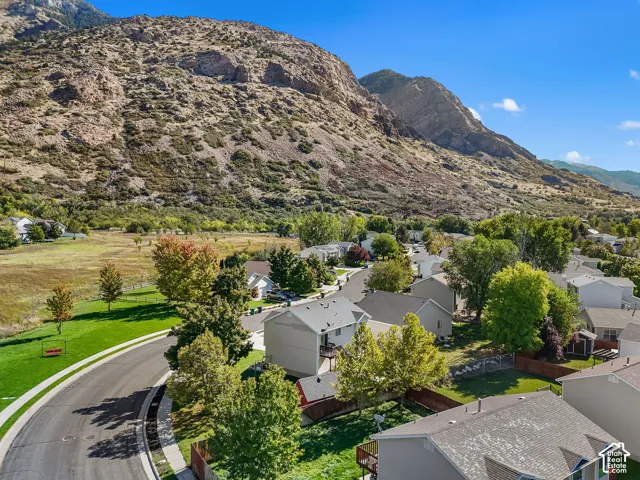 Aerial perspective of a residential neighborhood featuring mountain topography, mature trees, and paved street infrastructure