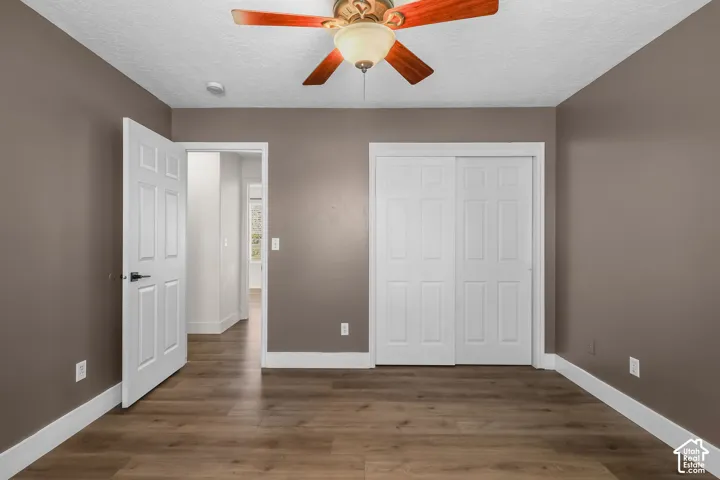 Room featuring wood-finish flooring, a ceiling fan with integrated lighting, and a dual-panel sliding closet door