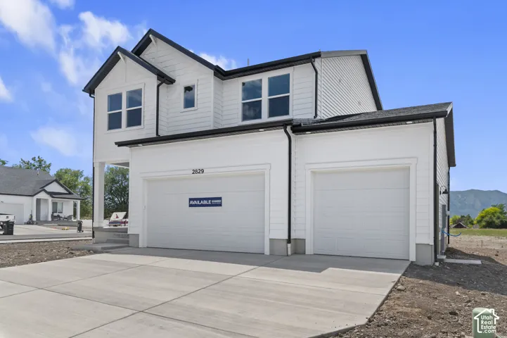 Two-story residence featuring white horizontal siding, dark roof trim, a concrete driveway, and an attached three-car garage
