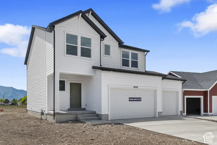 Two-story exterior featuring white horizontal siding, dark roof shingles, a three-car garage, and a covered front porch entry