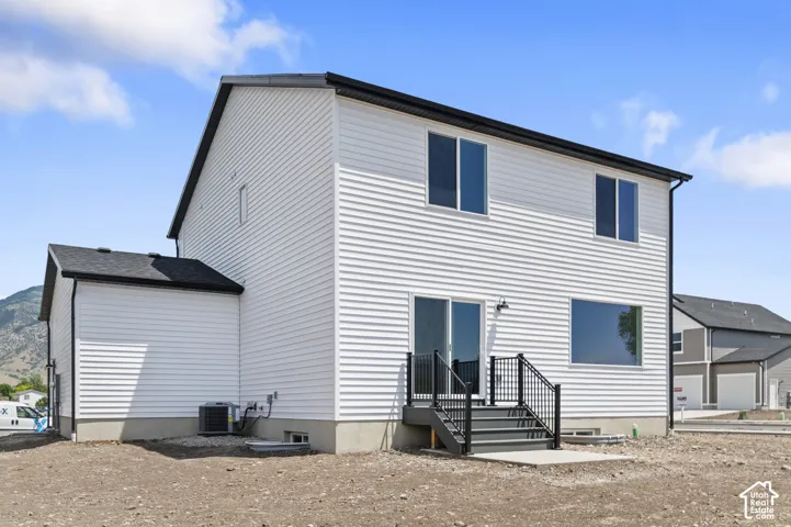 Two-story exterior featuring horizontal white siding, a contrasting dark shingle roof, sliding glass patio doors, and a set of exterior stairs with black metal railings