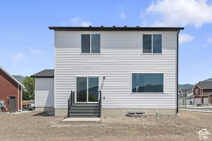 Two-story exterior featuring white horizontal siding, dark metal roof trim, sliding glass door with stairs, and large fixed-pane window
