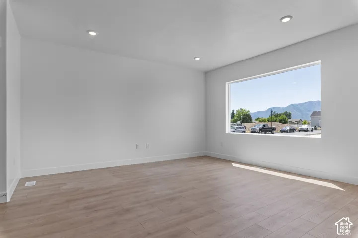 Room featuring wood-finish flooring, recessed lighting, and a large picture window with mountain scenery