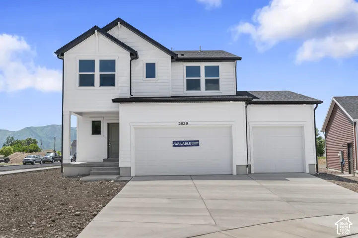 Two-story residence featuring white horizontal siding, a gabled roofline, a three-car garage, and mountain scenery