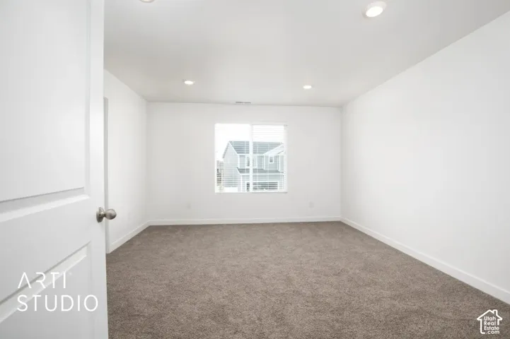 Neutral interior room featuring plush carpeting, recessed lighting, and a window with white casing
