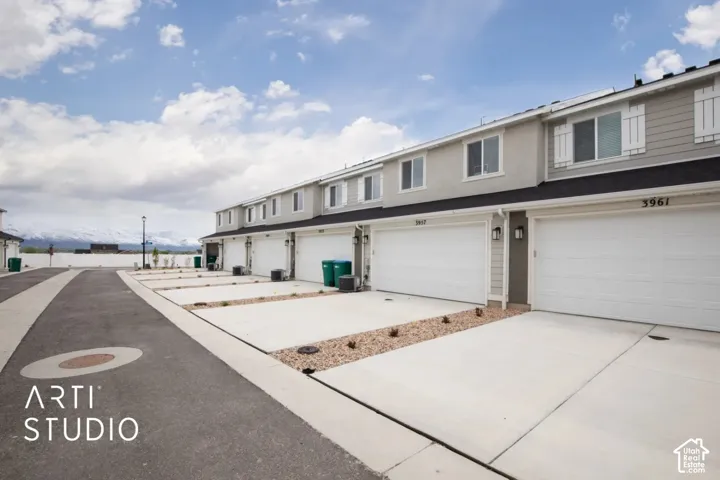 Multi-level exterior featuring horizontal lap siding, attached multi-car garages, shuttered windows, and a mountain backdrop