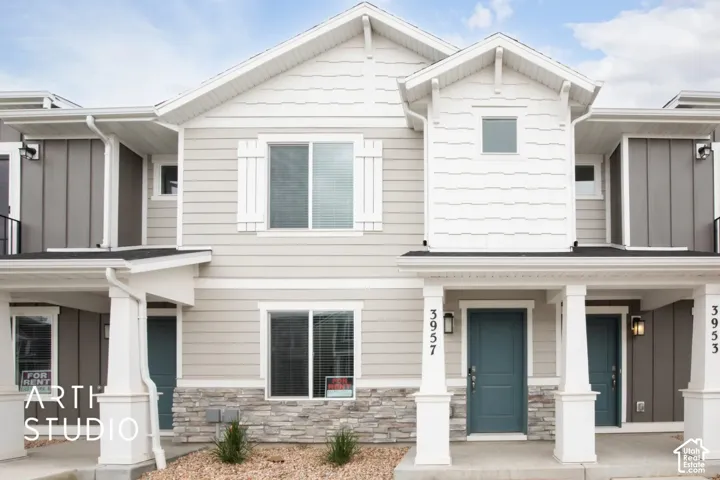 Multi-family exterior featuring horizontal lap and vertical board-and-batten siding, stone veneer accents, covered entry porches with square columns, and white trim detailing