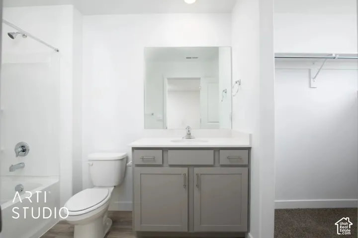 Bathroom featuring a gray vanity with a neutral solid-surface countertop, an integrated sink, a wall-mounted mirror, and a tub-shower combination with chrome hardware