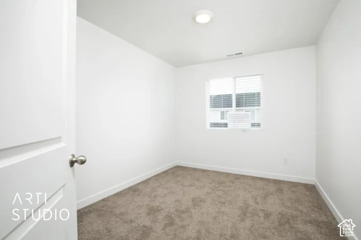Interior space featuring neutral wall-to-wall carpeting, crisp white walls, a single-hung window with built-in blinds, and a recessed ceiling light fixture