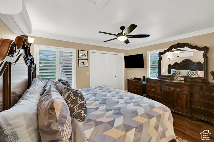 Interior space featuring wood-finish flooring, white plantation shutters, a ceiling-mounted light fixture with fan, and wall-mounted climate control unit