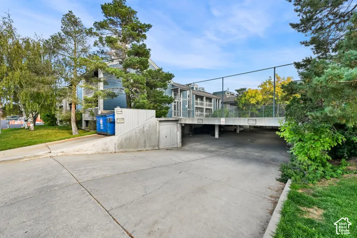 Exterior structure featuring covered parking, concrete driveway, and mature landscaping