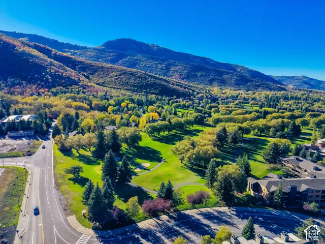 Aerial perspective featuring expansive mountain terrain, mature evergreen and deciduous trees, and manicured green space