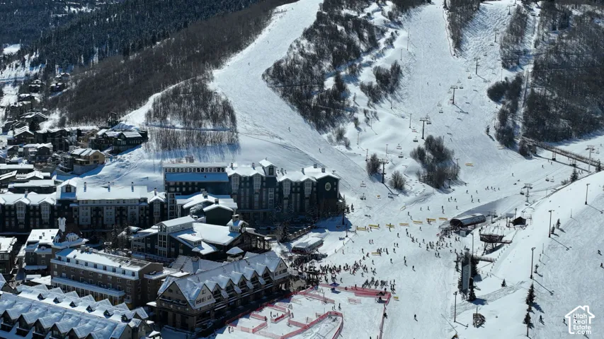 Aerial perspective featuring multi-story residential architecture with peaked rooflines, heavy timber accents, and stone-veneer cladding located at the base of a mountain slope