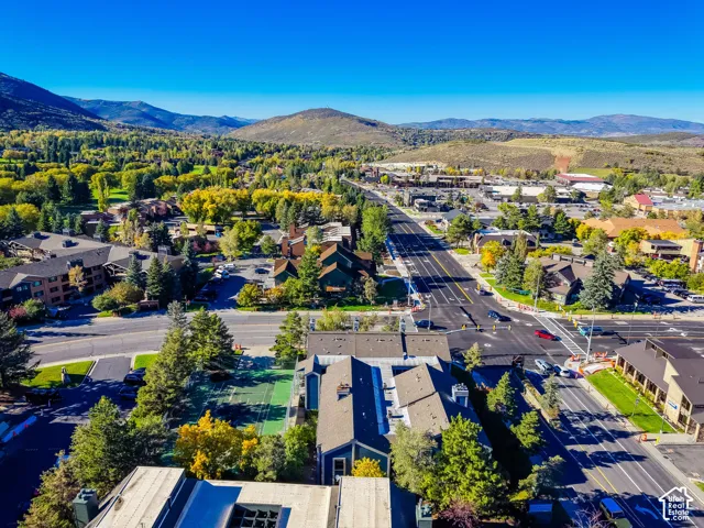Aerial perspective showcasing multi-level structures with pitched rooflines and onsite hardcourt surfacing, complemented by surrounding mature trees and a mountain backdrop