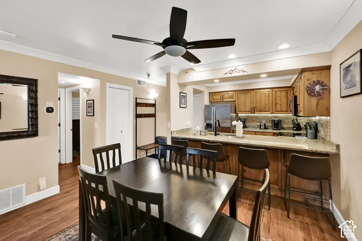 Kitchen featuring natural wood cabinetry, stone-surface breakfast bar, recessed lighting, and wood-finish flooring