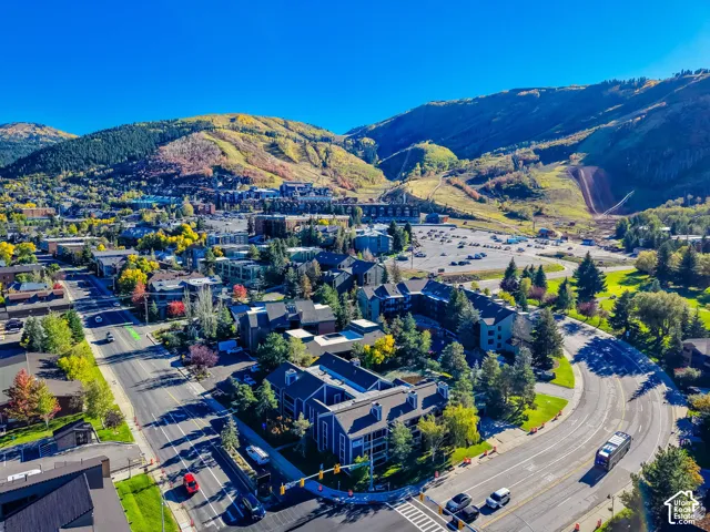 Aerial perspective featuring multi-story residential buildings with shingled roofing, set against a mountainous landscape