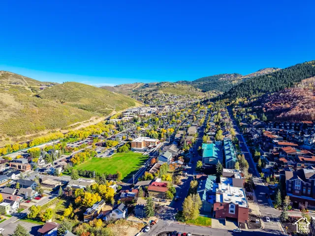 Aerial perspective of a mountain town featuring expansive valley terrain, dense deciduous vegetation, and established street grids