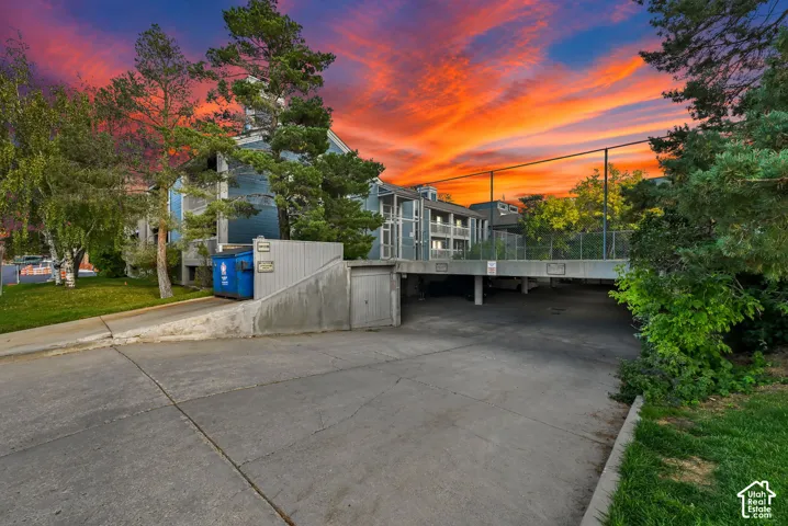 Multi-level exterior featuring wood-style siding, covered parking area, and concrete hardscaping