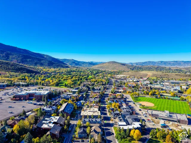 Aerial perspective showcasing mountain surroundings, mature deciduous trees, and expansive green space