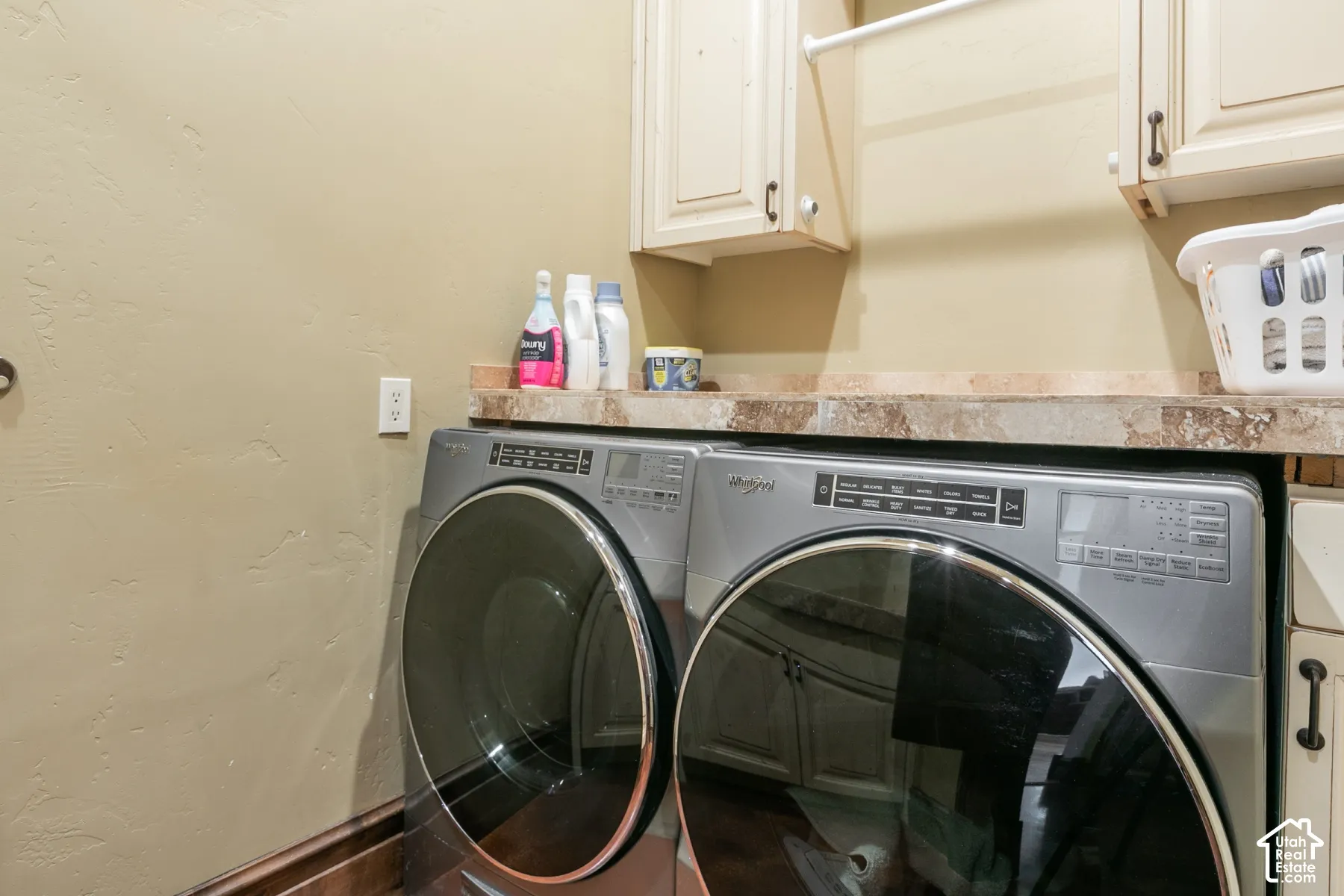 Laundry space featuring solid-surface countertops, wall-mounted cabinetry, and a mounted garment hanging rod