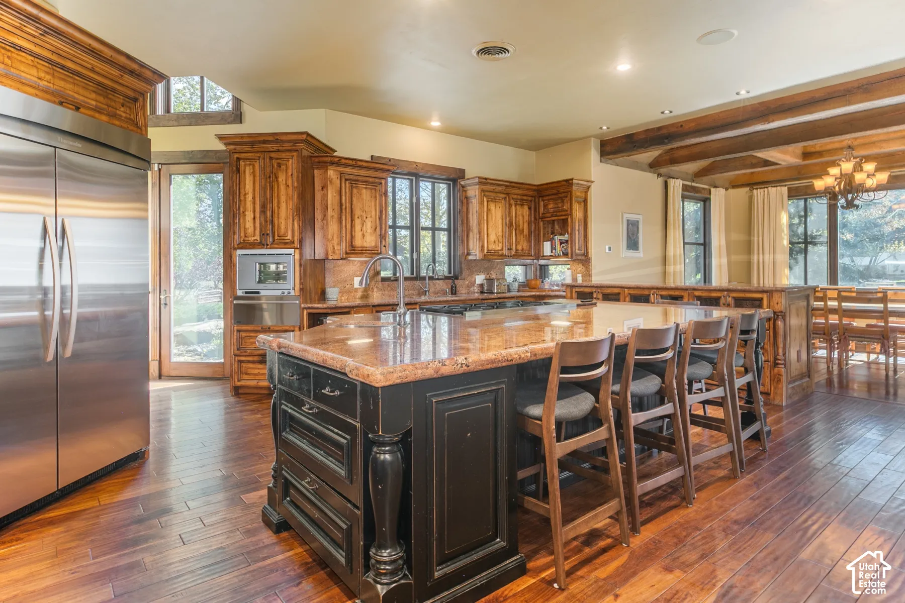 Kitchen featuring natural wood cabinetry, oversized center island with a stone countertop, stainless steel refrigerator, recessed ceiling lighting, and wood-finish flooring