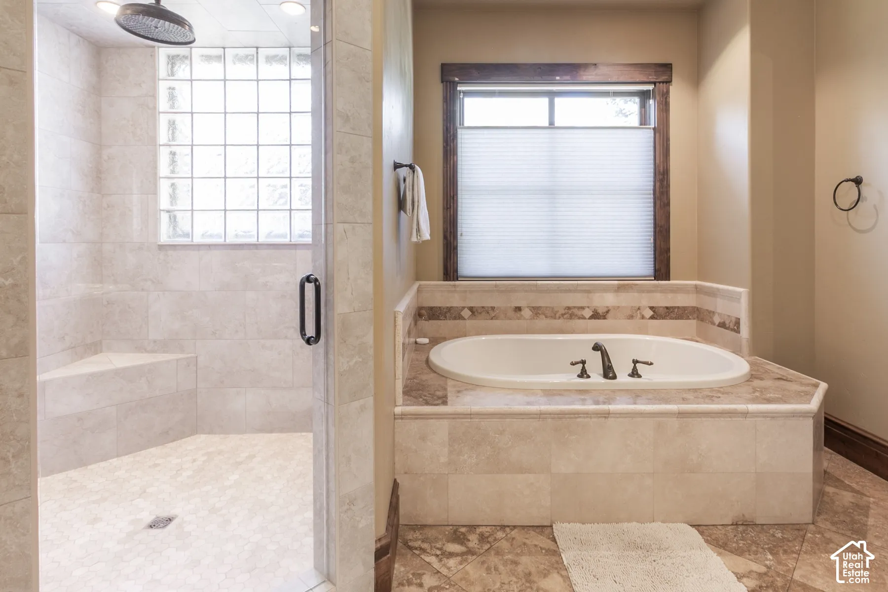 Walk-in shower with stone tile surround, integrated bench seat, and glass block window