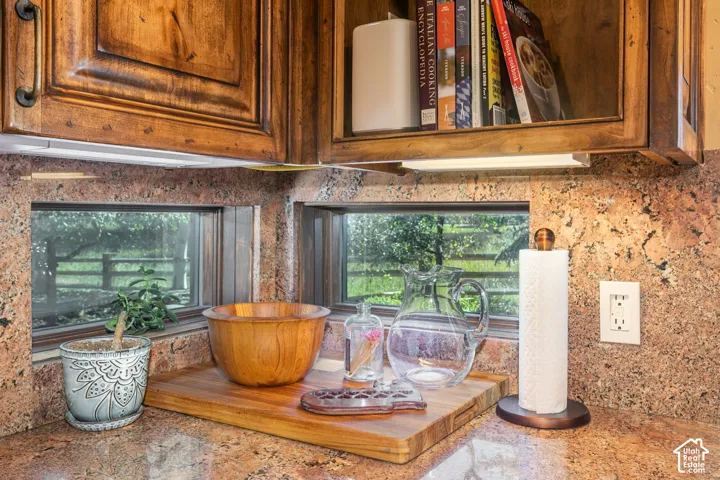 Custom raised-panel cabinetry with bronze-finish hardware, natural stone backsplash, and recessed horizontal windows