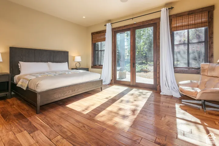 Hardwood flooring, natural wood trim, and glass paneled doors with exterior access