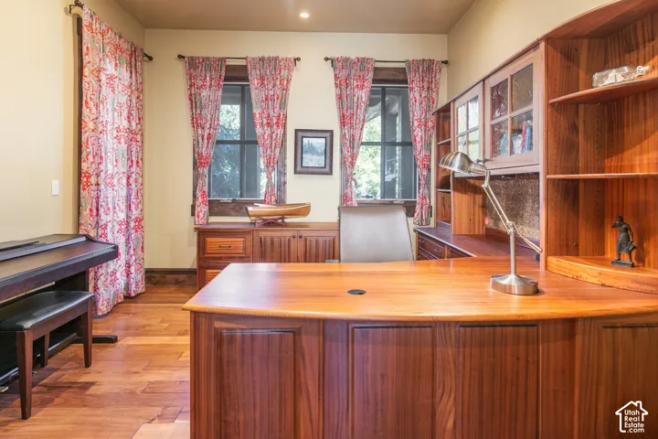 Built-in solid wood cabinetry and desk workspace, expansive windows with wood trim, and wood-finish flooring