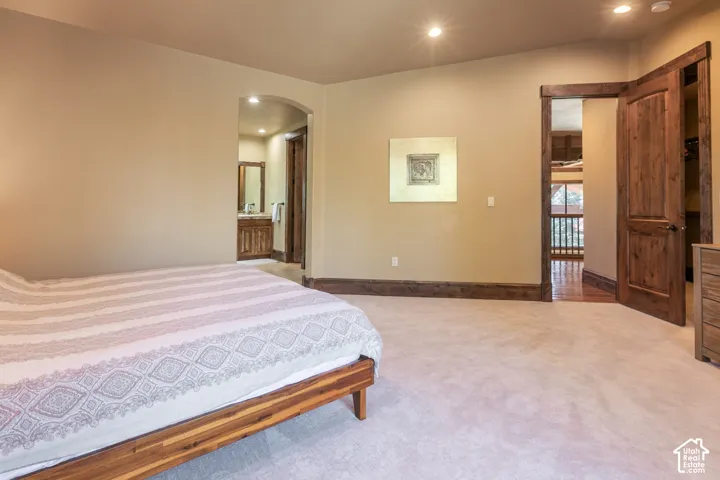 Neutral carpeting, recessed lighting, and solid wood-finish door frames featuring arched and square-cased entryways