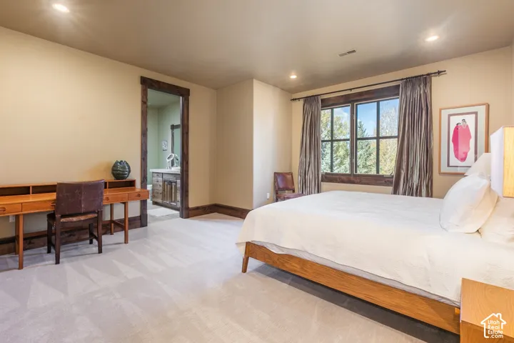 Neutral-toned bedroom featuring recessed lighting, carpeted flooring, and dark wood window and door casing