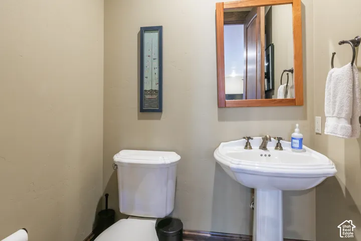 White pedestal sink with antique-style brass hardware, complemented by a wood-framed wall mirror and a decorative towel ring