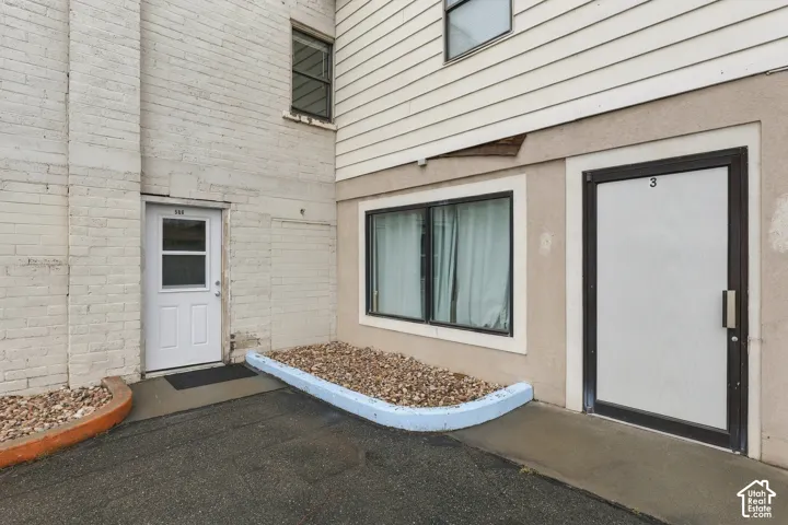Exterior featuring a mixed-material facade of painted brick and horizontal siding, stone-filled landscape beds with concrete curbing, and multiple individual entry points