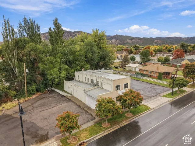 Multi-level commercial structure featuring expansive asphalt parking surfaces, mature landscaping, and mountain backdrop
