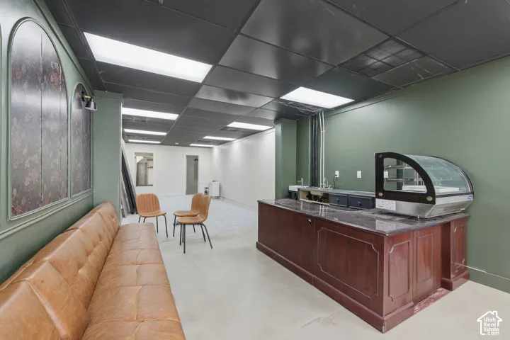 Custom built-in wood service counter, arched wall paneling with decorative inlay, recessed ceiling lighting, and polished concrete flooring