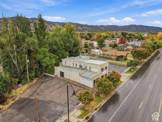 Multi-level structure featuring a flat roof and asphalt-paved lot with mountain backdrop and mature tree line