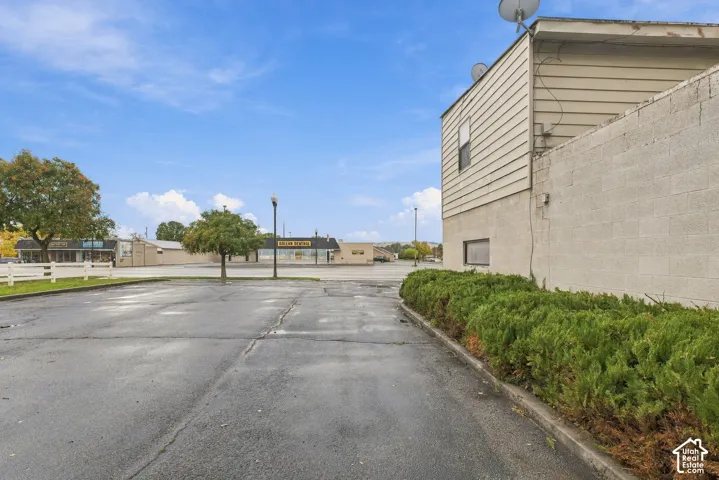 Paved parking area featuring a concrete block retaining wall and manicured shrubbery