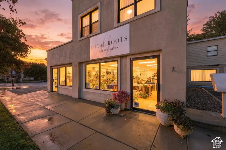 Two-story stucco commercial building featuring expansive storefront windows, glass-paneled entry doors, and concrete sidewalk frontage