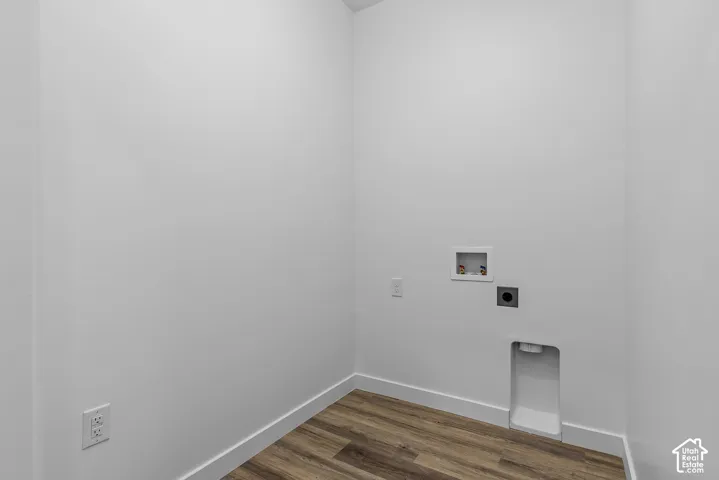 Utility alcove featuring wood-finish flooring, white walls, and dedicated washer and dryer hookups