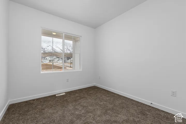 Neutral interior featuring crisp white walls, neutral carpeting, and a double-pane window with mountain scenery