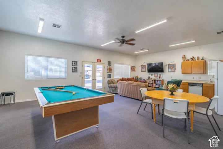Open-concept area featuring high ceilings, fluorescent lighting, ceiling fan, and built-in cabinetry with integrated sink and dishwasher
