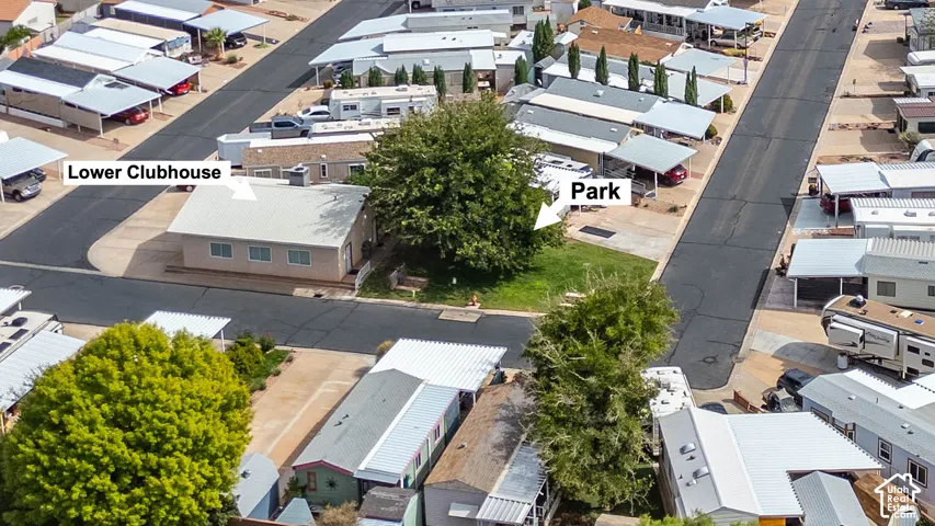 Aerial perspective of the community, featuring a clubhouse, park space with mature trees, and paved streets