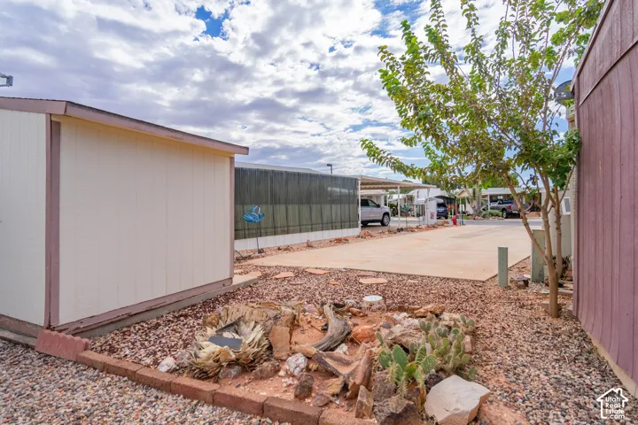 Exterior storage structure with vertical siding, concrete driveway, and rock-based landscaping featuring assorted cacti and stone edging