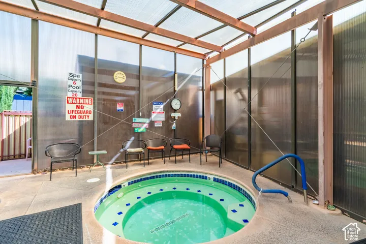 Enclosed spa featuring a circular basin, tiled interior finish, concrete surround, and a translucent, wood-framed overhead structure