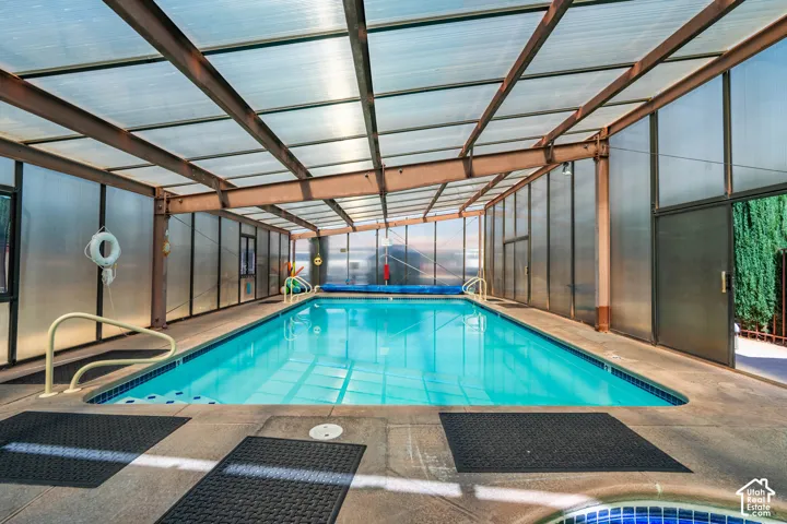 Enclosed pool structure featuring a translucent roof, steel framing, integrated entry handrails, and surrounding hardscaping