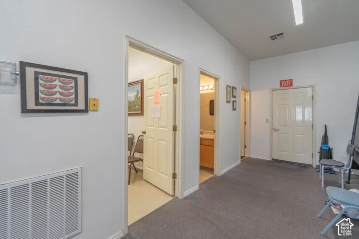 Interior hallway featuring gray carpeting, neutral walls, multiple solid-core passage doors, and recessed linear lighting