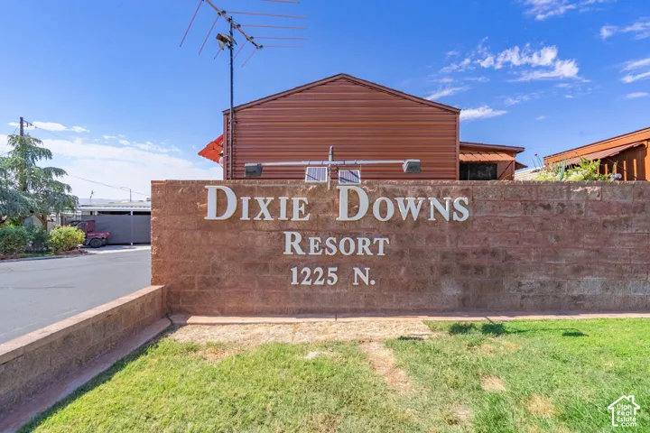 Masonry block wall signage with dimensional lettering and integrated landscape lighting, situated on a lot with paved street access and grass landscaping