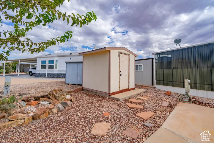 Exterior storage shed with a concrete foundation, stone-accented xeriscaping, and a natural stone paver pathway