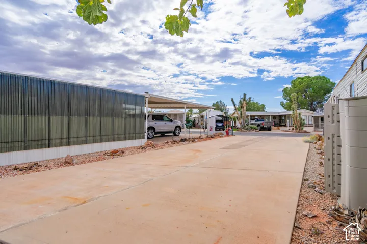 Concrete driveway featuring a covered carport, metal exterior siding, and xeriscape landscaping